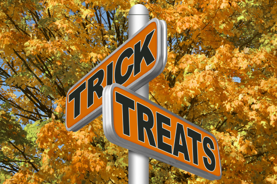 Two orange signs against orange-yellow leaves: one says "Trick" and the other says "Treats" in black writing